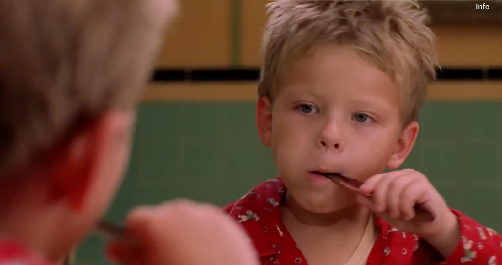 a young boy brushing his teeth in front of a mirror