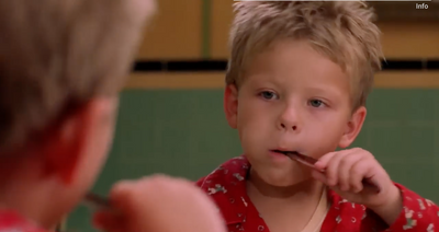 a young boy brushing his teeth in front of a mirror