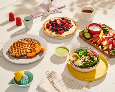 a table topped with plates of food and a bowl of fruit