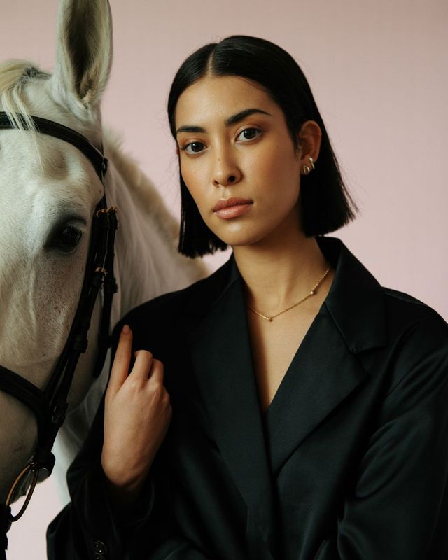 a woman standing next to a white horse