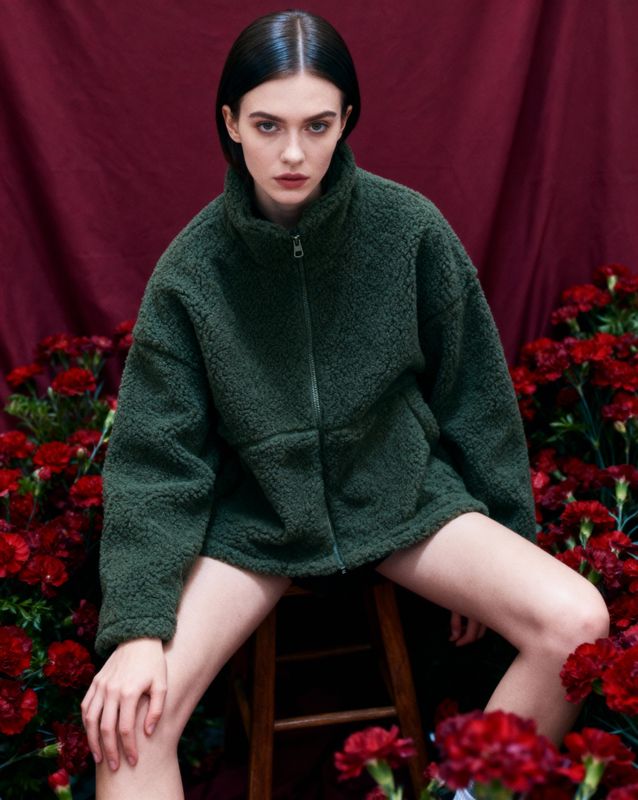a woman sitting on a stool in front of flowers