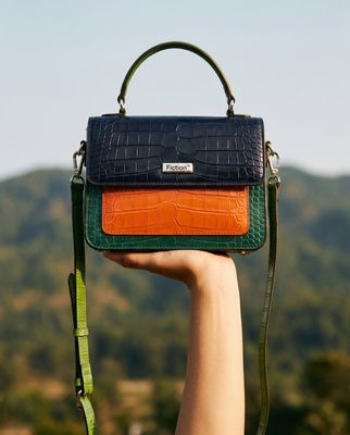 a hand holding a purse in front of a mountain