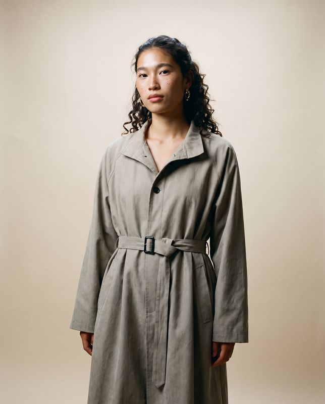a woman in a trench coat standing in front of a wall