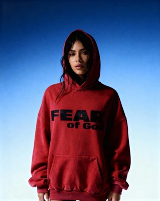 a woman wearing a red hoodie that says fear of god