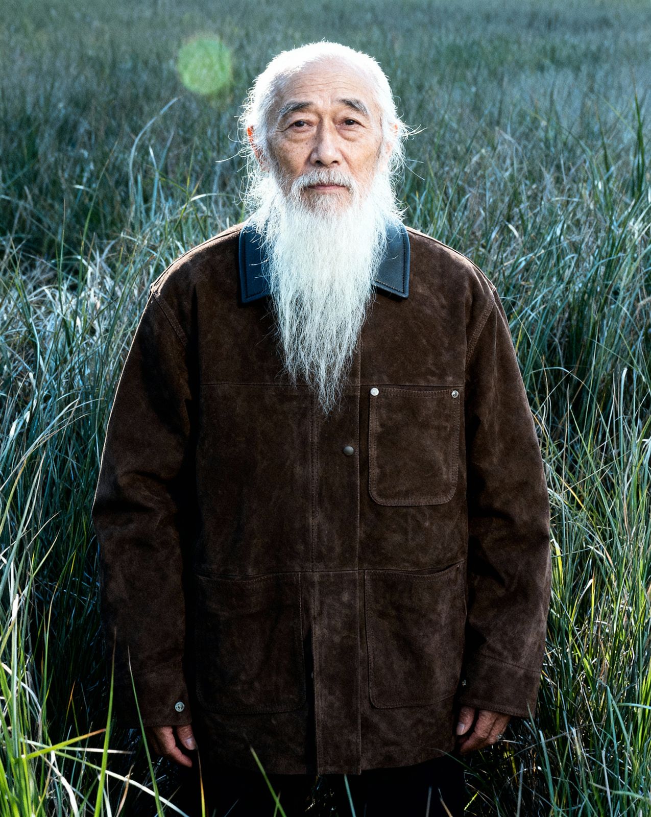 a man with a long white beard standing in a field