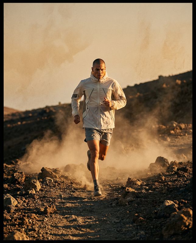 a man running down a dirt road in the desert