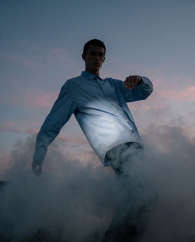 a man in a blue shirt is standing in the clouds