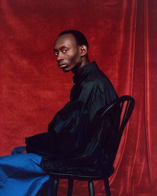 a man sitting on a chair in front of a red background