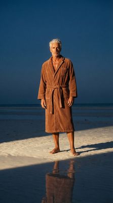 a man in a bathrobe standing on a beach