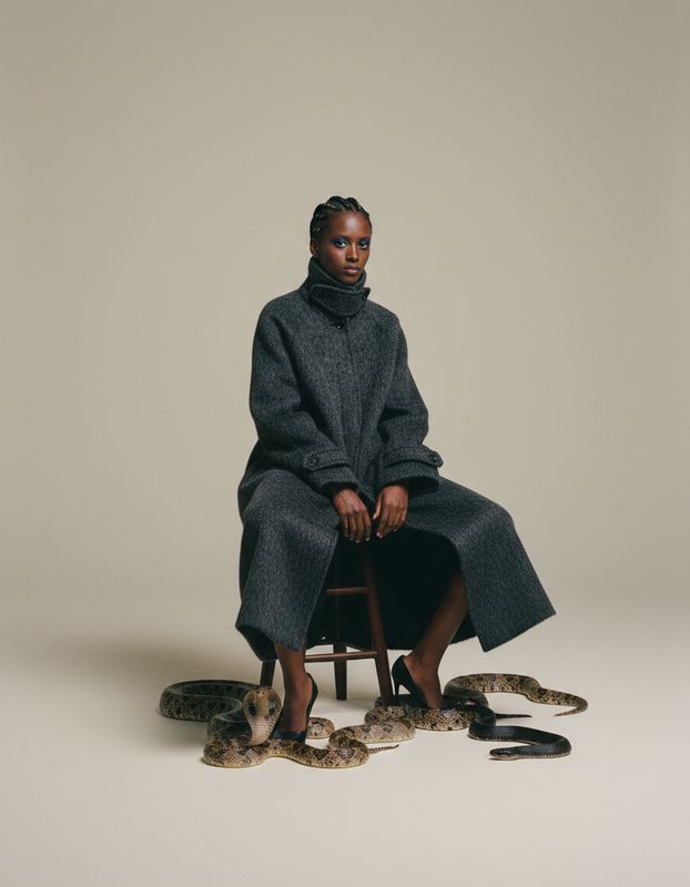 a woman sitting on a chair with snakes around her