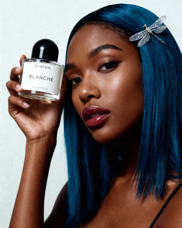 a woman with blue hair holding a bottle of blanche