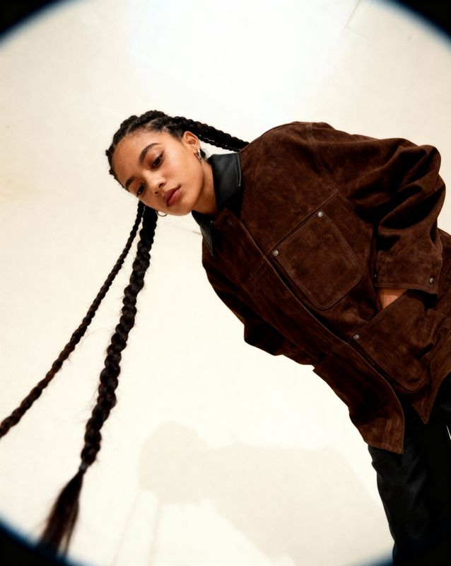 a woman with long braids standing in front of a mirror
