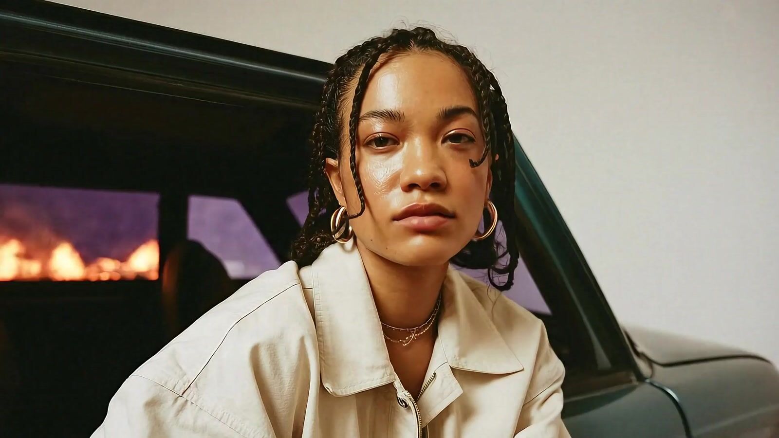 a woman with dreadlocks sitting in front of a car