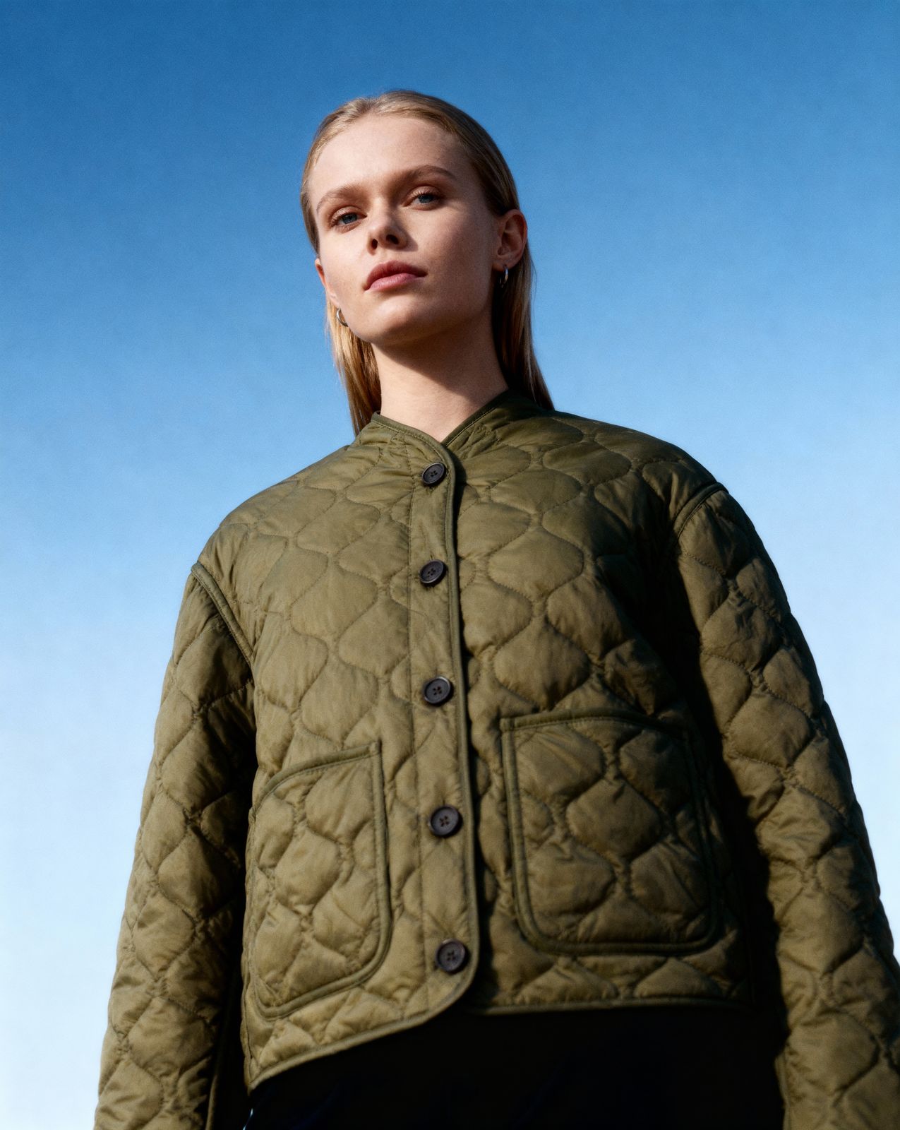 a woman wearing a green jacket and black pants