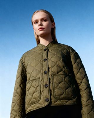 a woman wearing a green jacket and black pants