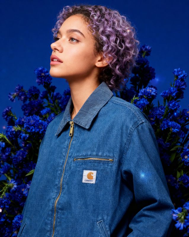 a woman with purple hair standing in front of blue flowers