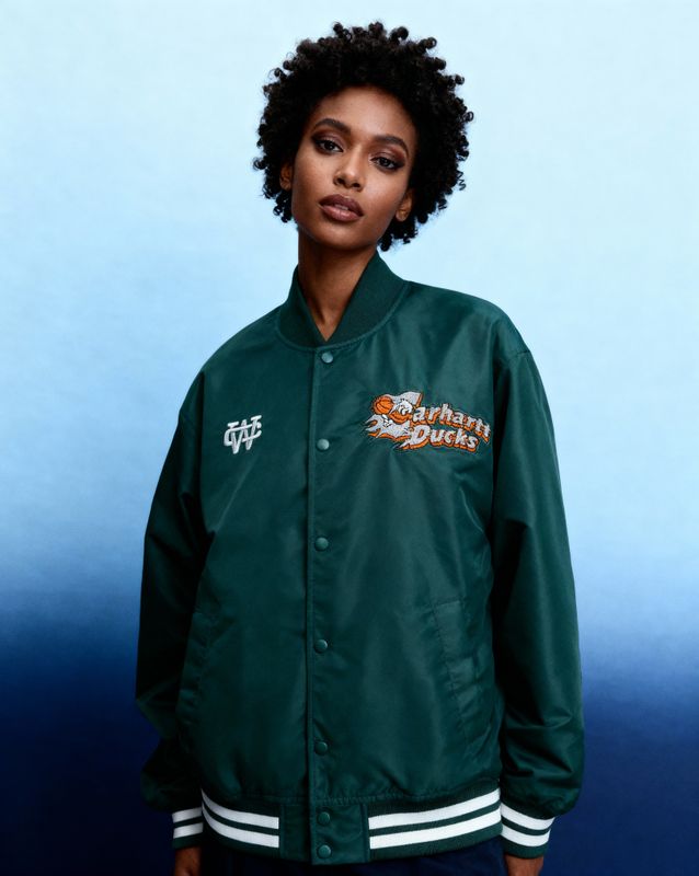 a woman standing in front of a blue background wearing a green jacket