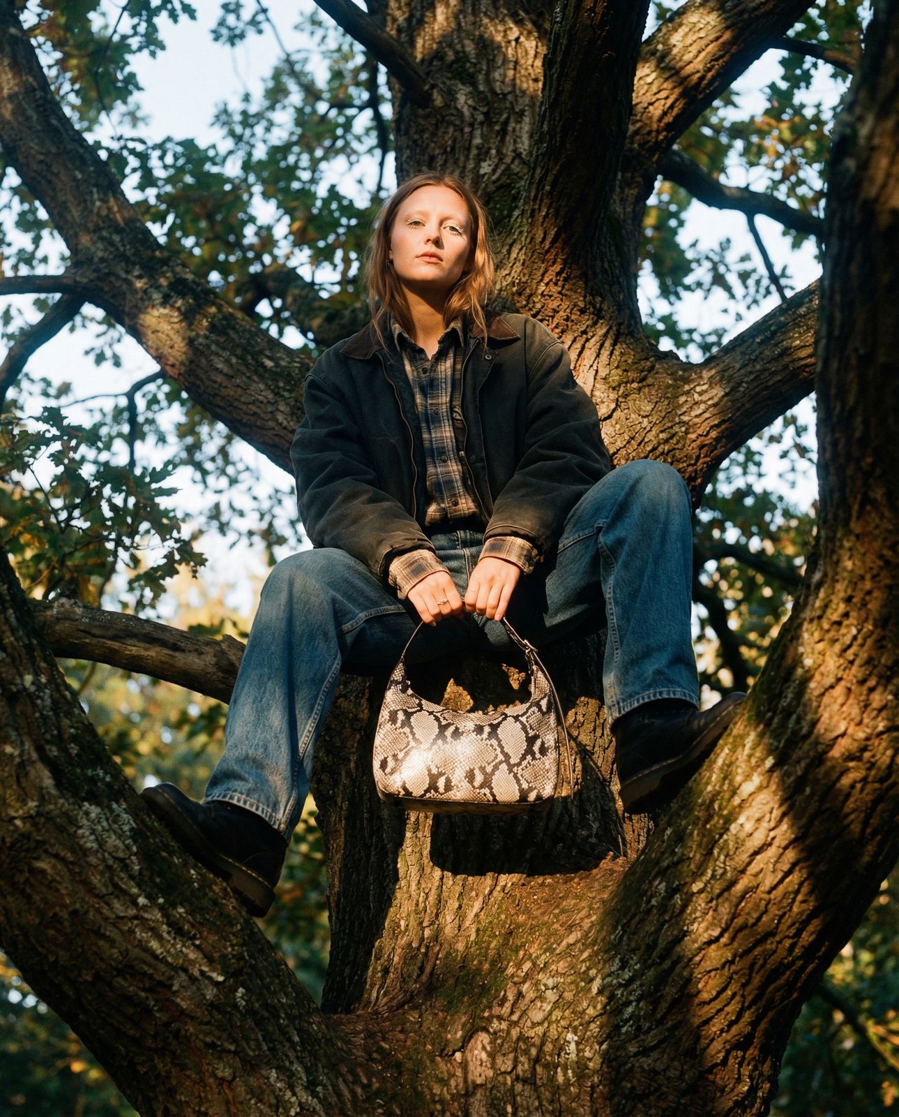 a person sitting in a tree with a handbag