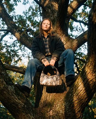 a person sitting in a tree with a handbag