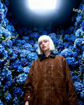 a woman standing in front of blue flowers