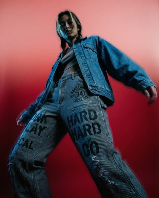 a man in a jean jacket and jeans is posing for a picture