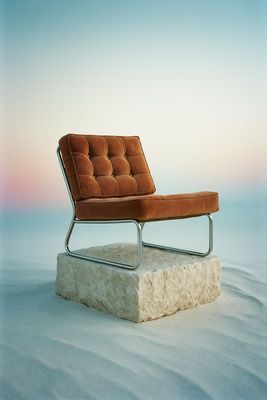 a chair sitting on top of a rock in the sand