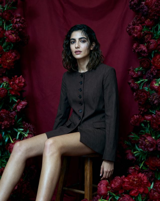 a woman sitting on a stool in front of flowers
