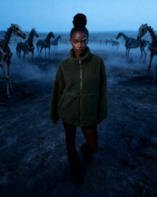 a woman standing in front of a herd of horses