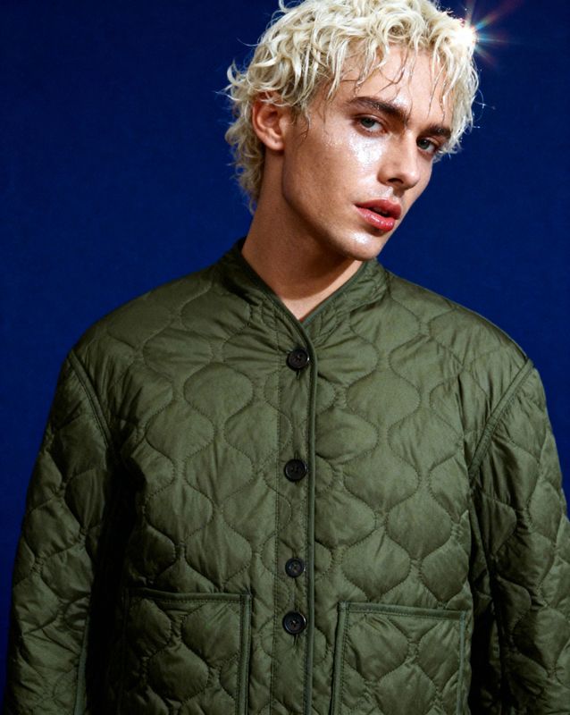 a man with blonde hair wearing a green jacket
