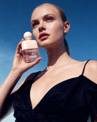 a woman in a black dress holding a bottle of perfume