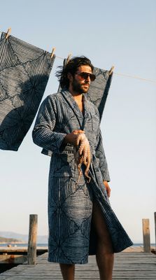 a man in a bathrobe holding two umbrellas