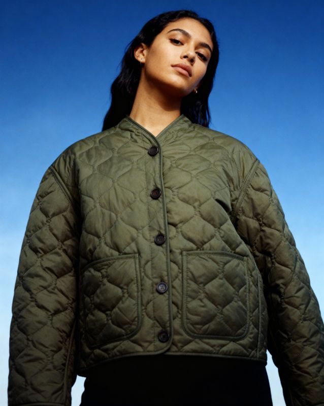 a woman wearing a green jacket and black pants