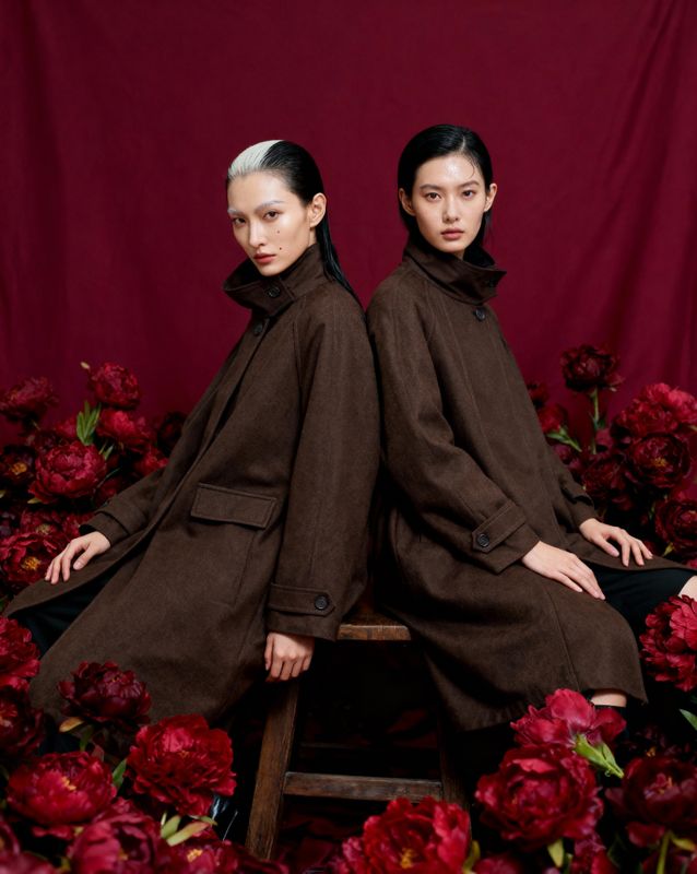 two women sitting on a chair surrounded by flowers