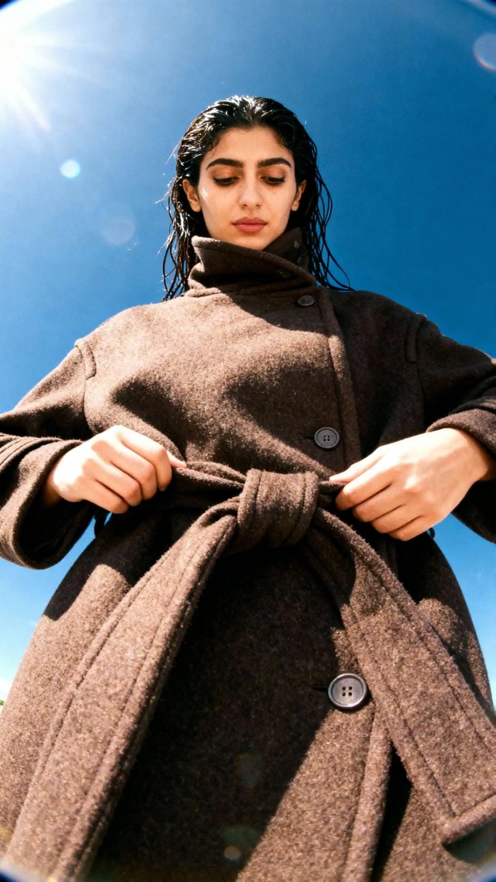a woman in a brown coat and a blue sky