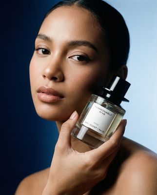 a woman holding a bottle of perfume in her hand