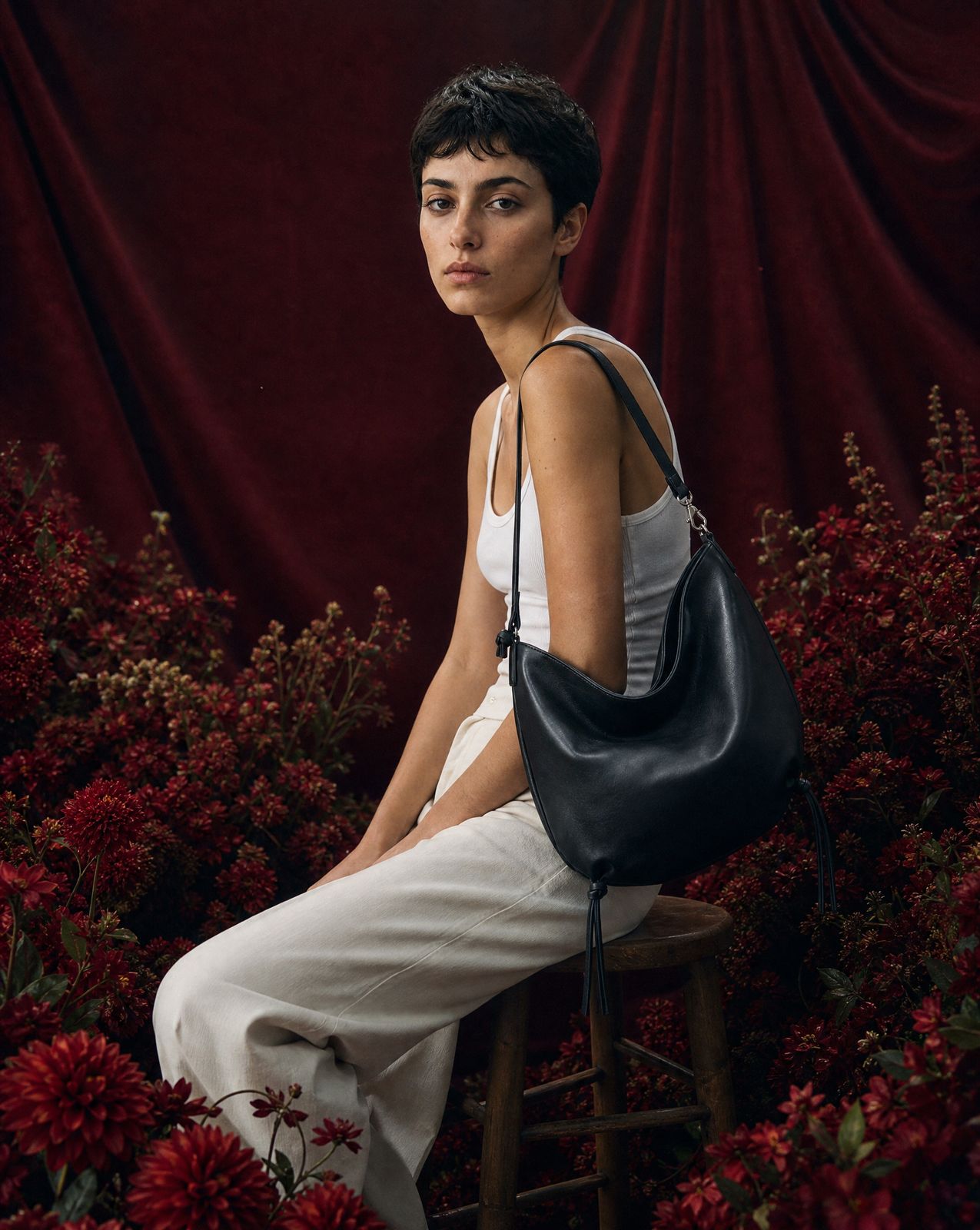 a woman sitting on a stool with a black bag