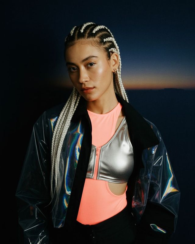 a woman with braids standing in front of a dark background