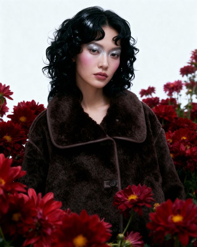 a woman standing in a field of red flowers