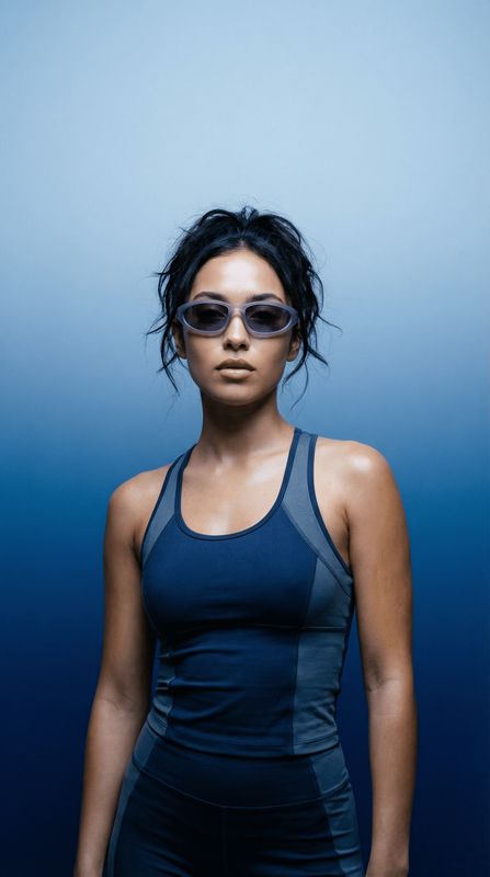 a woman in a blue tank top and sunglasses
