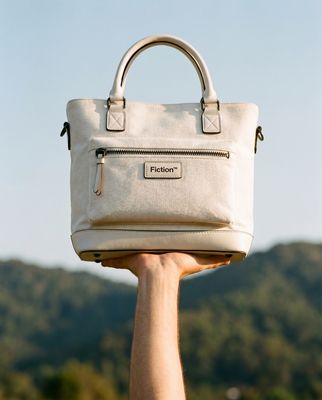 a person holding a white purse over their head