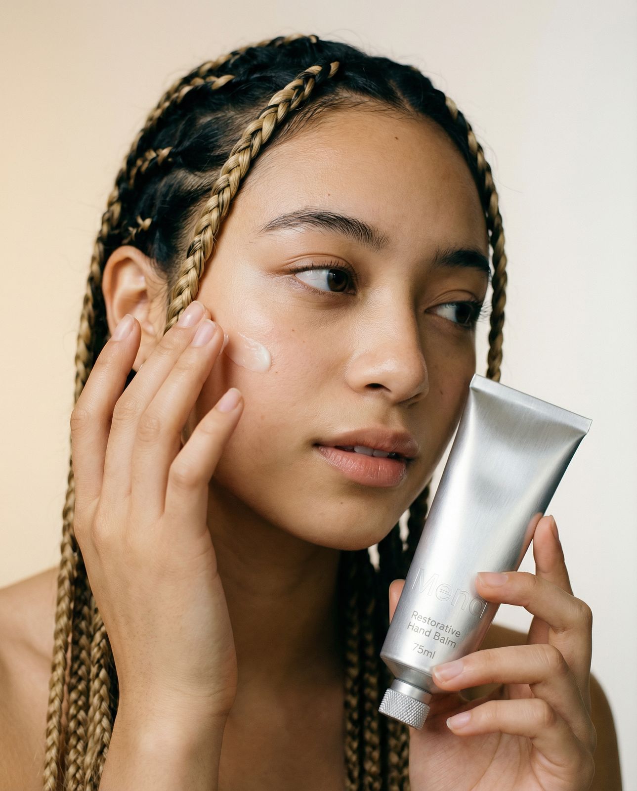a woman holding a tube of cream in front of her face