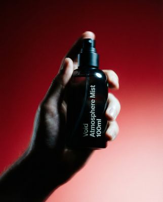 a hand holding a black bottle with a red background