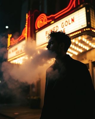 a man standing in front of a theater smoking a cigarette