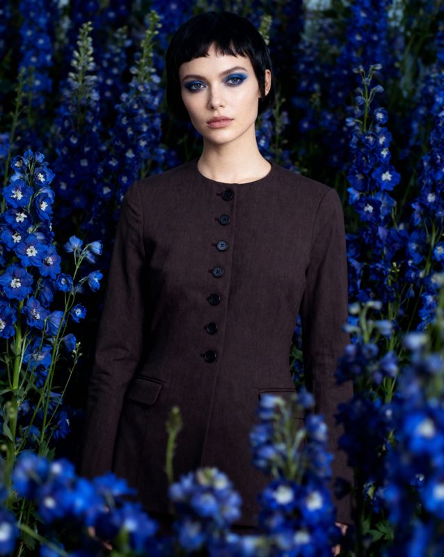 a woman standing in a field of blue flowers