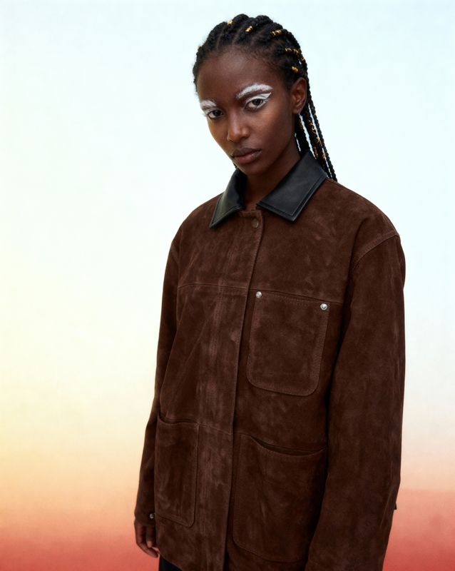 a woman with braids wearing a brown jacket
