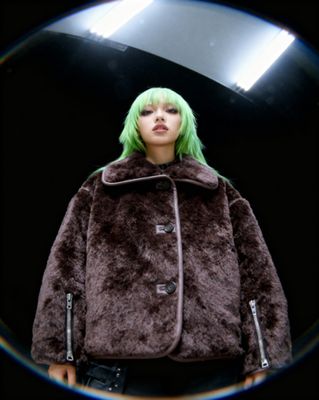 a woman with green hair wearing a brown coat
