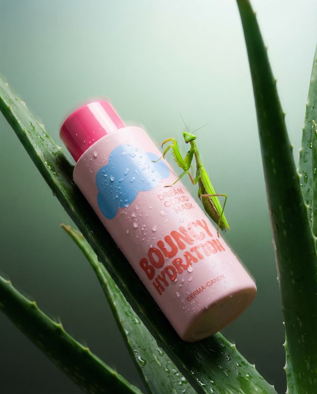 a green insect sitting on top of a pink bottle