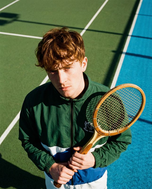 a young man holding a tennis racquet on a tennis court