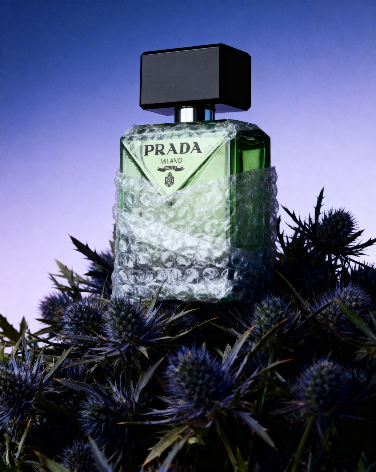 a bottle of prada perfume sitting on top of a bush
