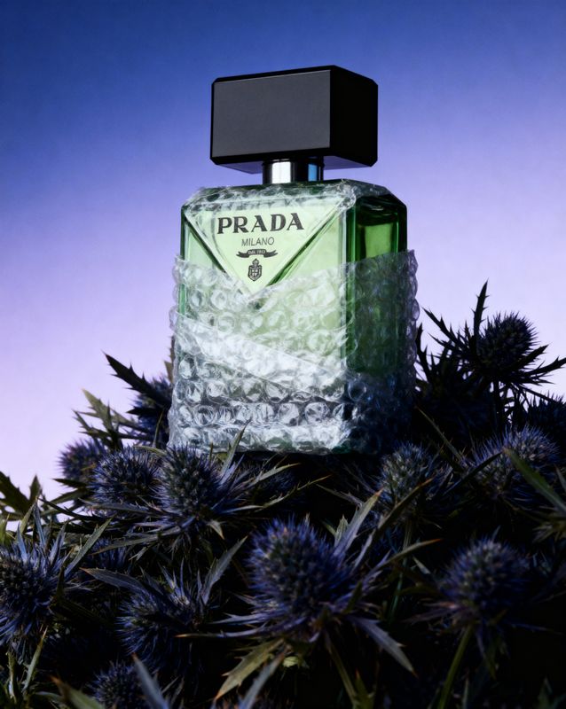 a bottle of prada perfume sitting on top of a bush